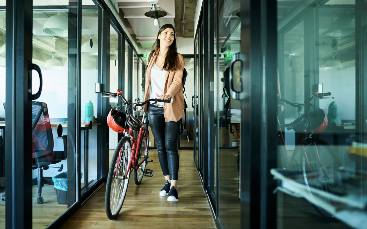 Woman wheeling bicycle out of office