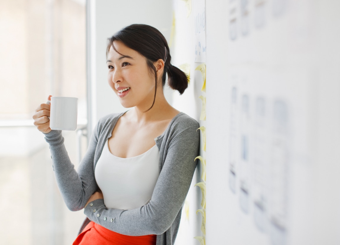 HR Manager standing in front of office whiteboard with a cup of coffee